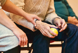 hand comforting older man holding a stress ball