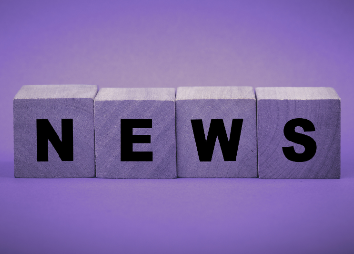 Wooden blocks spelling out the word "NEWS" are arranged in a row against a purple background.