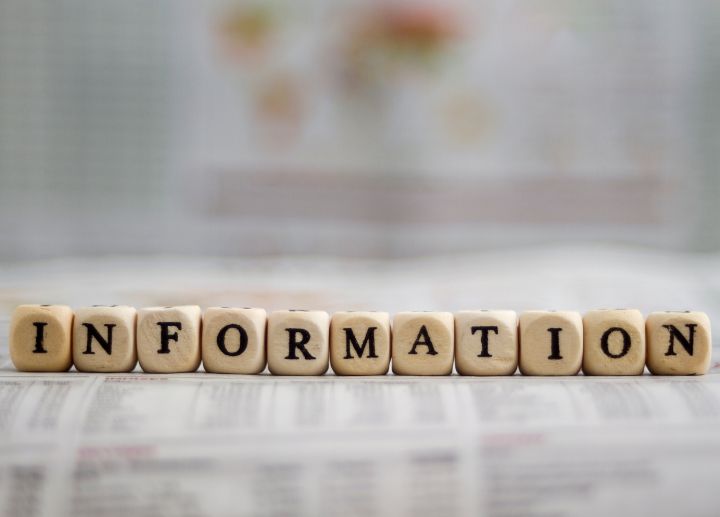 Wooden letter blocks spelling the word ‘INFORMATION’ placed on a newspaper