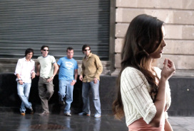 boys leaning against a building leering at a girl