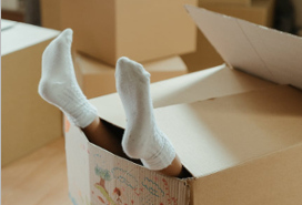feet of a child sticking up from open cardboard box