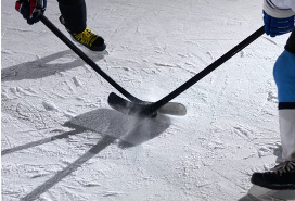 skates and sticks of two hockey players on snowy ice