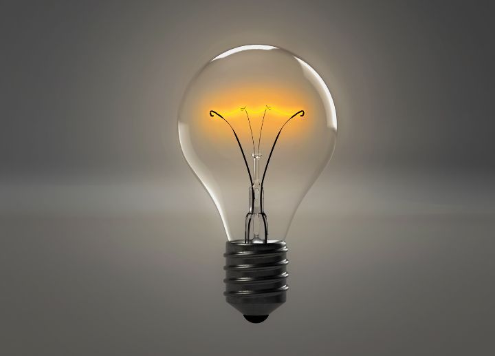 Close‑up of a lightbulb glowing against a neutral background.